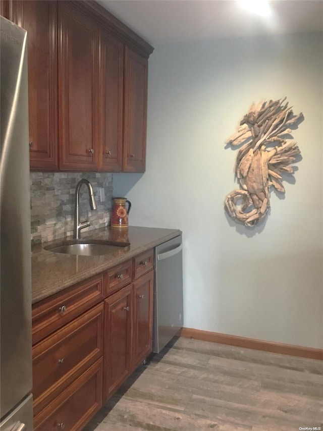 kitchen featuring tasteful backsplash, stainless steel appliances, sink, dark stone countertops, and light hardwood / wood-style floors