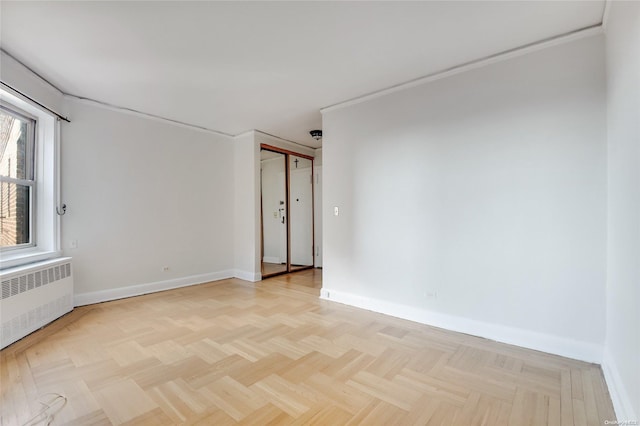 spare room featuring radiator heating unit and light parquet flooring