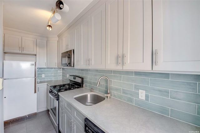 kitchen with appliances with stainless steel finishes, backsplash, sink, dark tile patterned flooring, and white cabinets