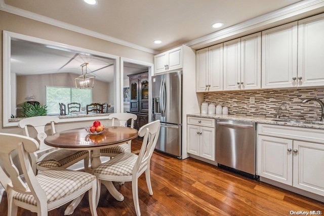 kitchen featuring sink, crown molding, hardwood / wood-style flooring, decorative light fixtures, and stainless steel appliances