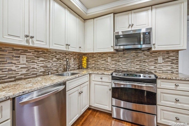 kitchen with white cabinets, sink, hardwood / wood-style flooring, decorative backsplash, and appliances with stainless steel finishes