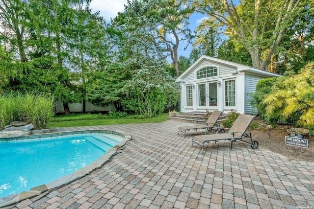 view of pool with french doors, a patio, and an outdoor structure