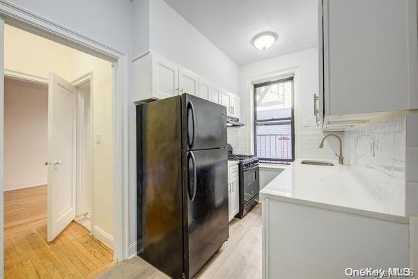 kitchen featuring black appliances, light hardwood / wood-style floors, white cabinetry, and sink