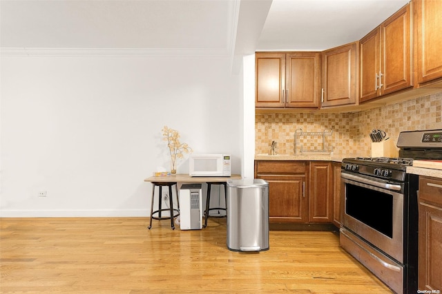 kitchen featuring decorative backsplash, light hardwood / wood-style flooring, crown molding, and stainless steel range with gas stovetop