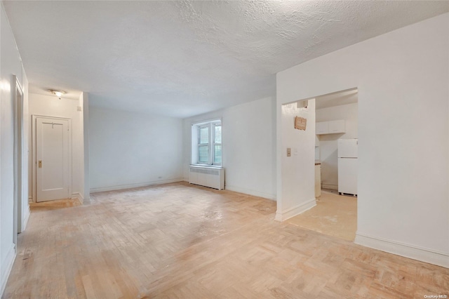 spare room featuring radiator, light parquet floors, and a textured ceiling