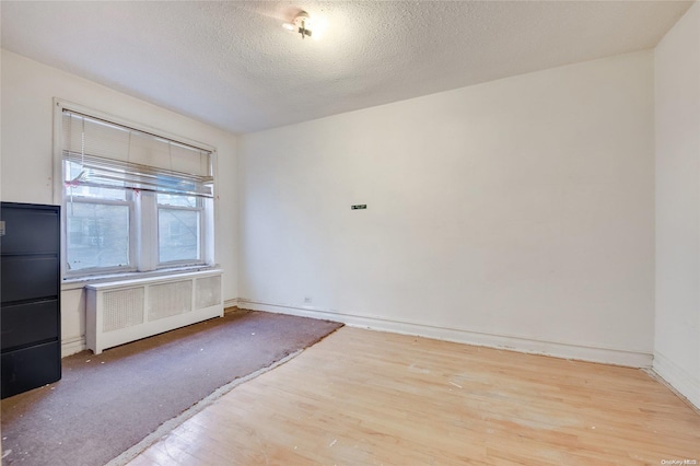 unfurnished room featuring a textured ceiling, light wood-type flooring, and radiator