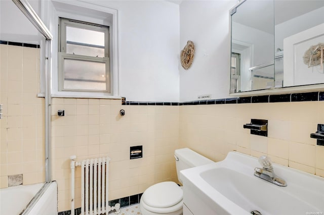 full bathroom with sink, toilet, radiator, and tile walls