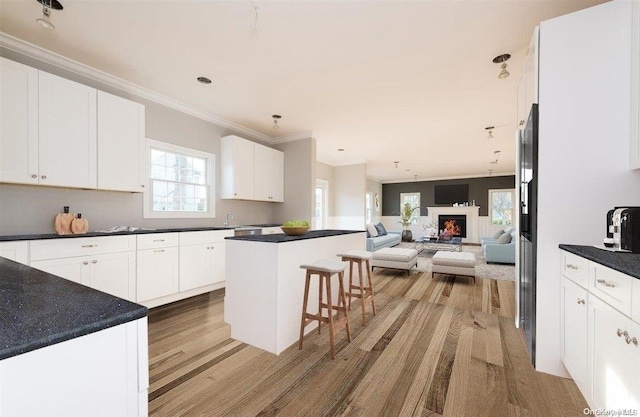 kitchen with a center island, white cabinets, a kitchen breakfast bar, ornamental molding, and light hardwood / wood-style floors