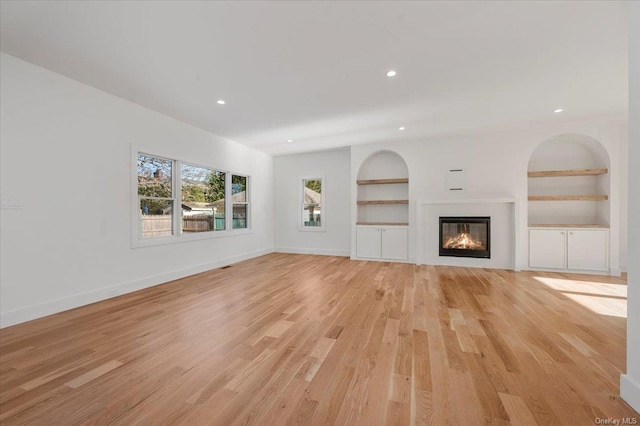 unfurnished living room with light wood-type flooring and built in features