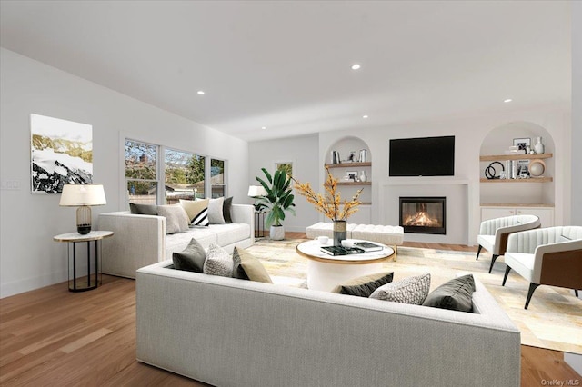 living room with built in shelves and light hardwood / wood-style flooring