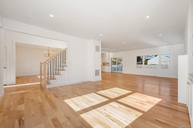 unfurnished living room with a notable chandelier and light hardwood / wood-style flooring