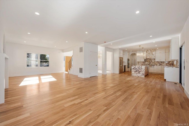 unfurnished living room with sink and light wood-type flooring