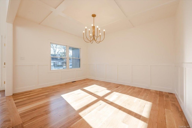 unfurnished room featuring hardwood / wood-style floors, coffered ceiling, and an inviting chandelier