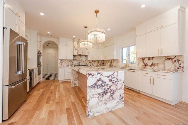 kitchen featuring white cabinetry, hanging light fixtures, stainless steel appliances, backsplash, and a kitchen island