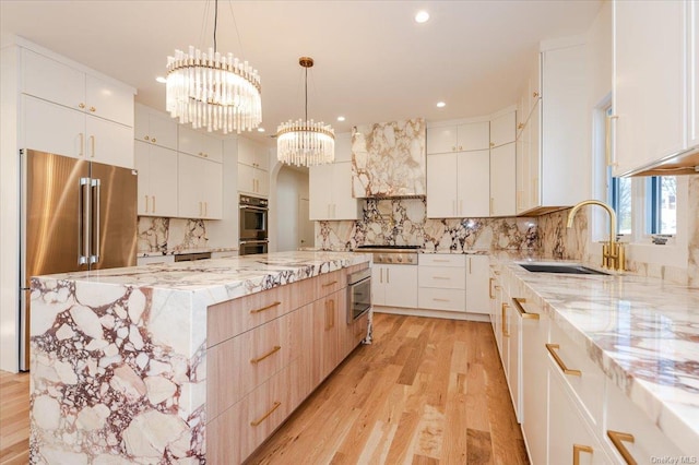 kitchen featuring stainless steel appliances, sink, pendant lighting, white cabinets, and a large island