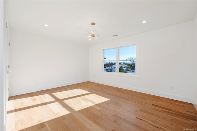 empty room with a notable chandelier and light hardwood / wood-style flooring