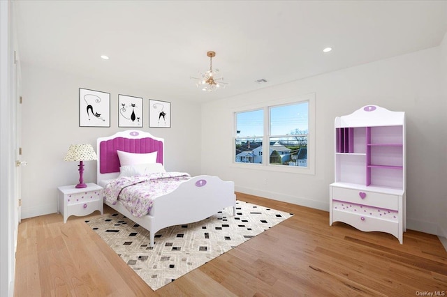 bedroom with light hardwood / wood-style floors and an inviting chandelier