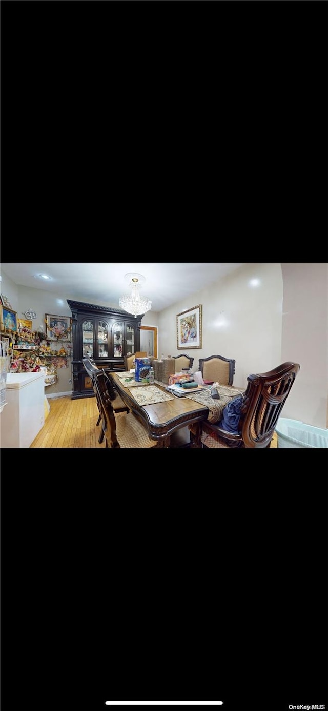 dining room with light wood-type flooring and a notable chandelier