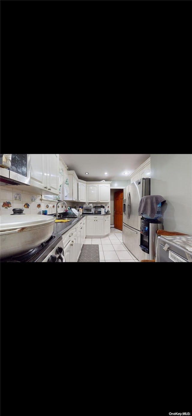 kitchen featuring sink, white cabinets, light tile patterned floors, and stainless steel refrigerator with ice dispenser