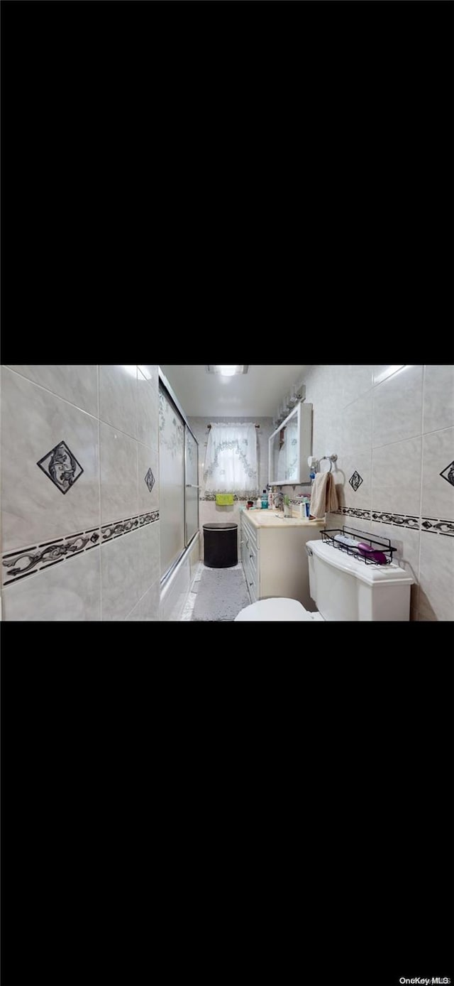 bathroom with tile walls and a shower with shower door