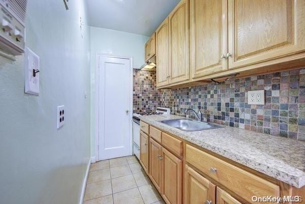 kitchen featuring tasteful backsplash, sink, light tile patterned floors, light brown cabinets, and white range with gas stovetop