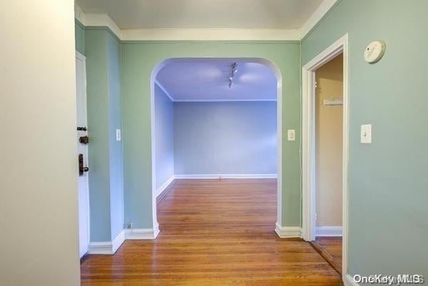 corridor with ornamental molding and light hardwood / wood-style flooring