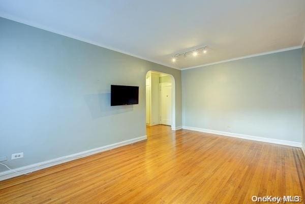 spare room featuring crown molding, rail lighting, and light hardwood / wood-style floors