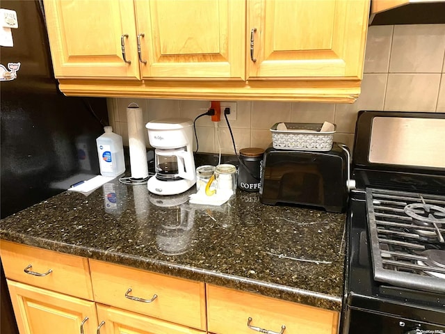 kitchen with backsplash, dark stone countertops, and black range