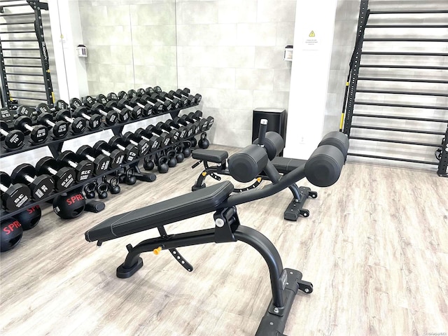 exercise room with tile walls and hardwood / wood-style flooring