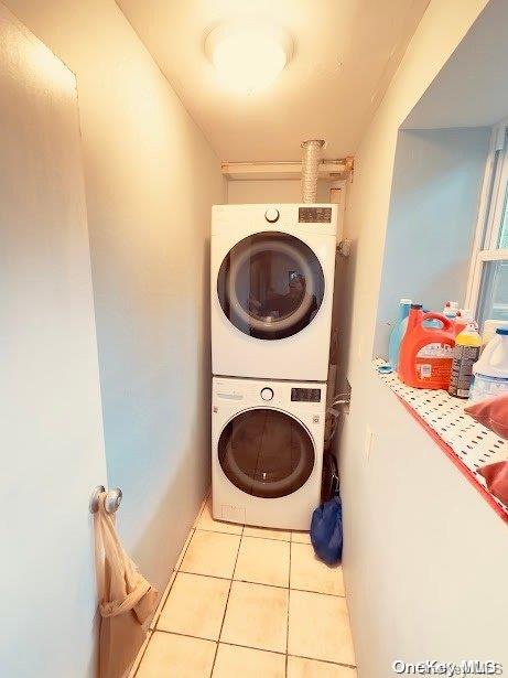 laundry room with stacked washer and dryer and light tile patterned flooring