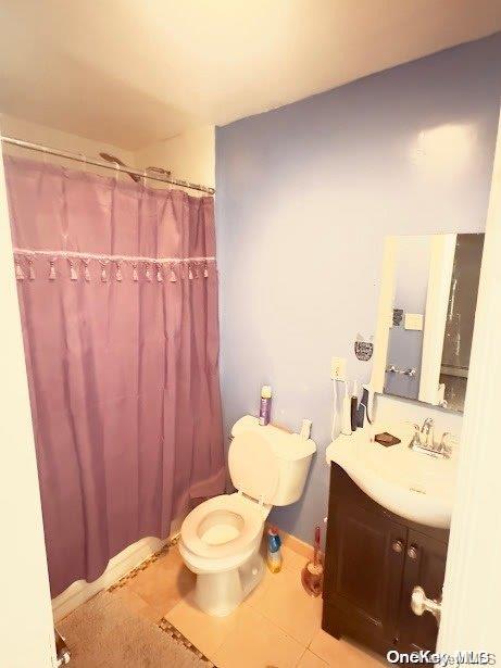 bathroom with toilet, vanity, and tile patterned floors