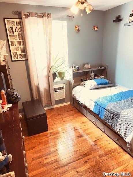 bedroom featuring ceiling fan, hardwood / wood-style floors, and a wall mounted air conditioner