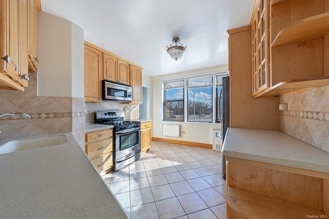 kitchen featuring sink, decorative backsplash, light tile patterned floors, light brown cabinetry, and appliances with stainless steel finishes