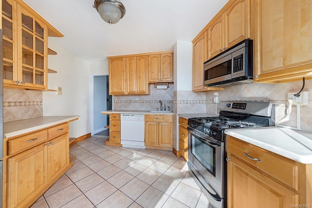 kitchen featuring backsplash, light tile patterned flooring, sink, and appliances with stainless steel finishes