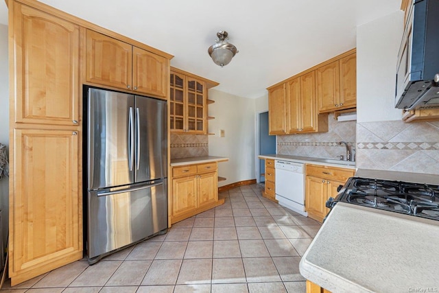 kitchen with backsplash, sink, light tile patterned floors, and stainless steel appliances