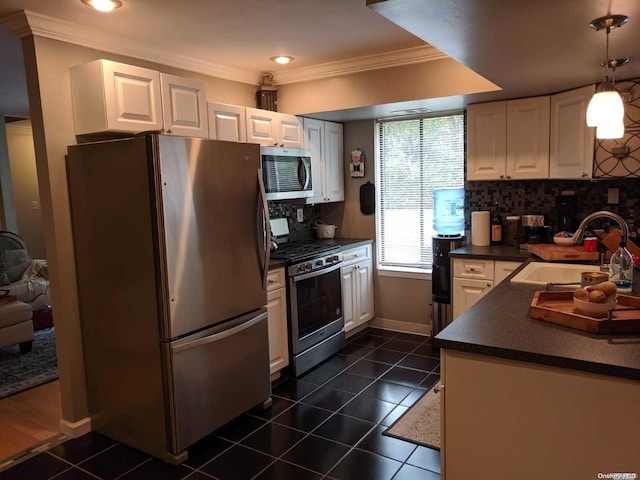 kitchen with tasteful backsplash, hanging light fixtures, dark tile patterned floors, and stainless steel appliances