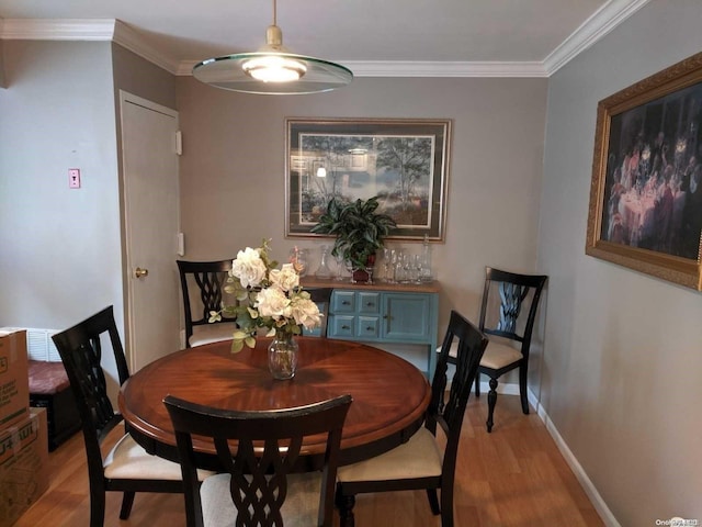 dining room with ornamental molding and light hardwood / wood-style flooring