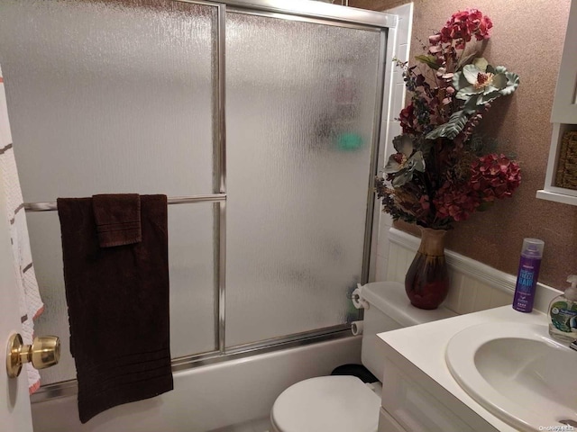 full bathroom featuring vanity, enclosed tub / shower combo, and toilet