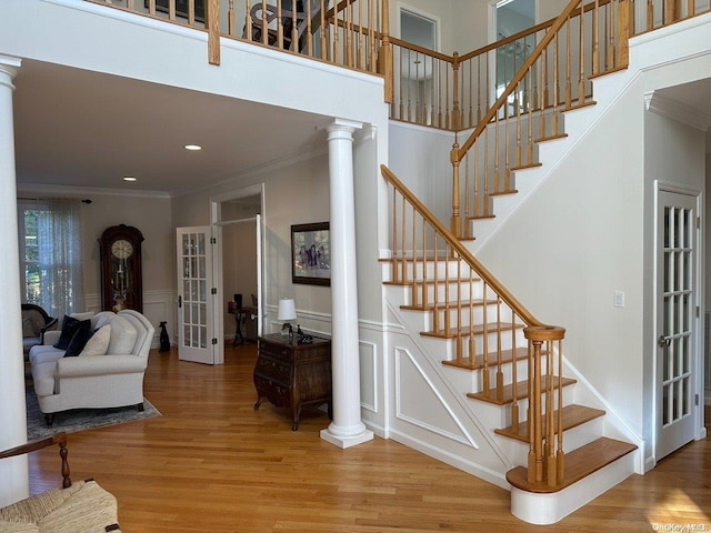 staircase featuring hardwood / wood-style floors, ornate columns, french doors, and crown molding