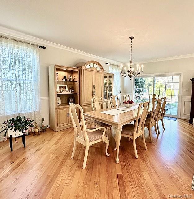 dining area featuring a chandelier, light wood-type flooring, and crown molding