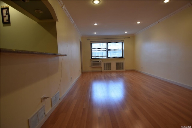 unfurnished room featuring hardwood / wood-style flooring, crown molding, and a wall unit AC