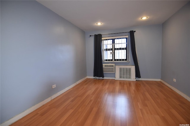 empty room with light wood-type flooring and a wall unit AC