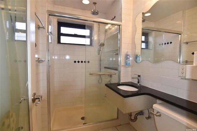 bathroom featuring tasteful backsplash, sink, a shower with door, and toilet