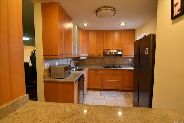 kitchen with light stone countertops, black fridge, white gas cooktop, stainless steel dishwasher, and decorative backsplash