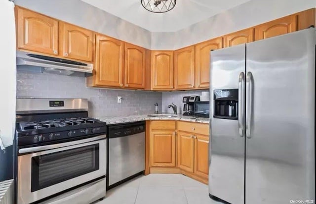 kitchen with sink, decorative backsplash, light tile patterned floors, appliances with stainless steel finishes, and light stone counters