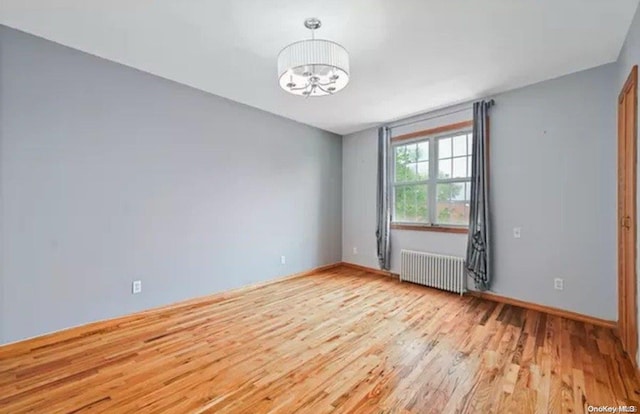 unfurnished room with a notable chandelier, light hardwood / wood-style floors, and radiator