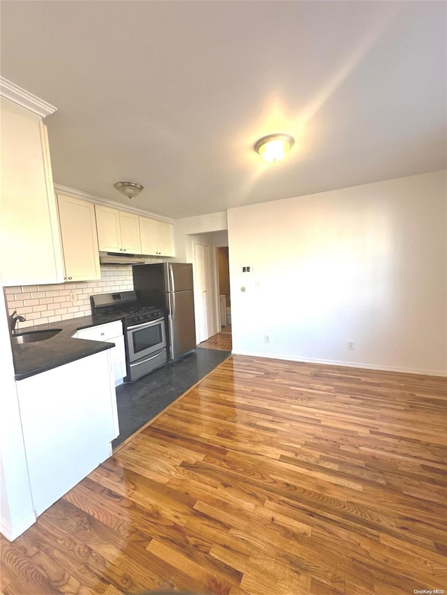 kitchen with tasteful backsplash, white cabinetry, dark wood-type flooring, and appliances with stainless steel finishes