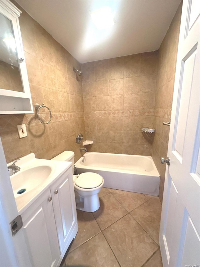 full bathroom with tile patterned floors, vanity, tiled shower / bath combo, tile walls, and toilet