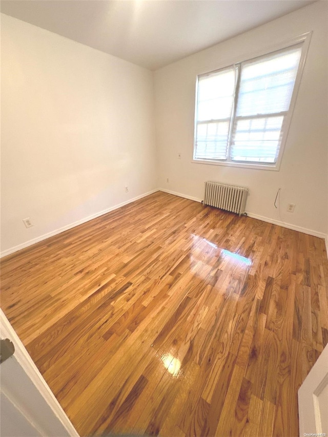 empty room with light hardwood / wood-style floors and radiator