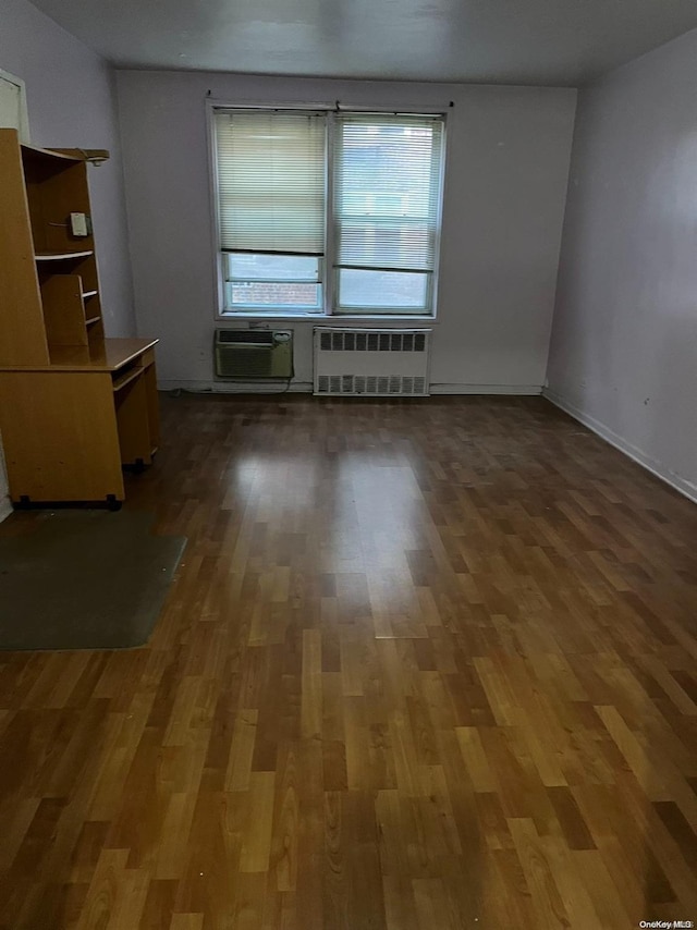 spare room featuring radiator, dark hardwood / wood-style flooring, and a wall mounted AC